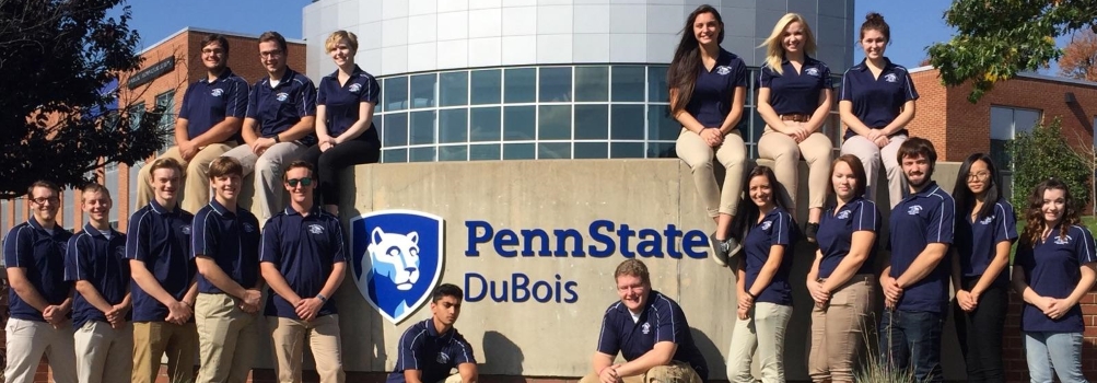 Campus Sign outside of DEF Building, with students Campus Sign outside of DEF Building, with students