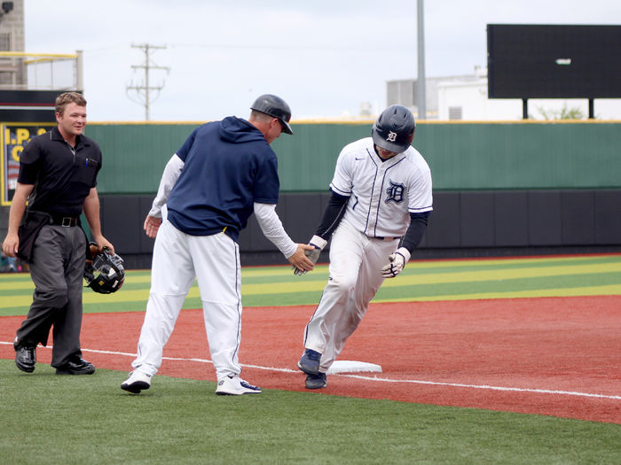 Penn State DuBois sophomore catcher Grant Lillard gets a low five from head coach Tom Calliari at third base after hitting a home run during the PSUAC championship game at Showers field in DuBois.