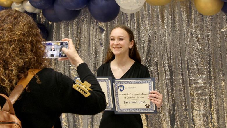Penn State DuBois student Savannah Ross pauses with her awards for a photo, taken by a family member, at the recognition and awards banquet at the PAW Center.