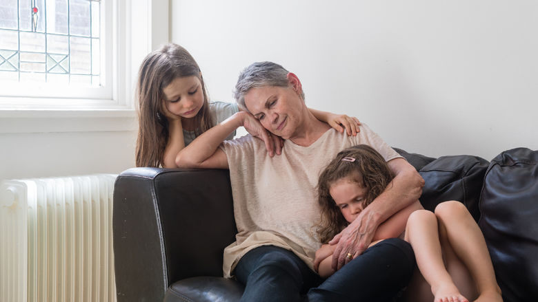 sad grandmother on couch with 2 granddaughters