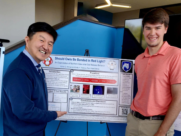 Two people stand in front of a research poster. 