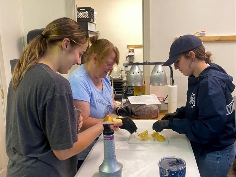 Penn State DuBois students Hannah Allen, left, and Justice Williams, right, work with a Soul Platter Café staff member to help prepare meals during the recent day of service.