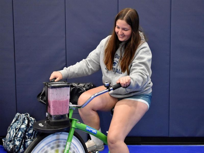 Penn State DuBois student Aleigha Geer pedals the smoothie bike during the 2023 Earth Day celebration at the PAW Center.