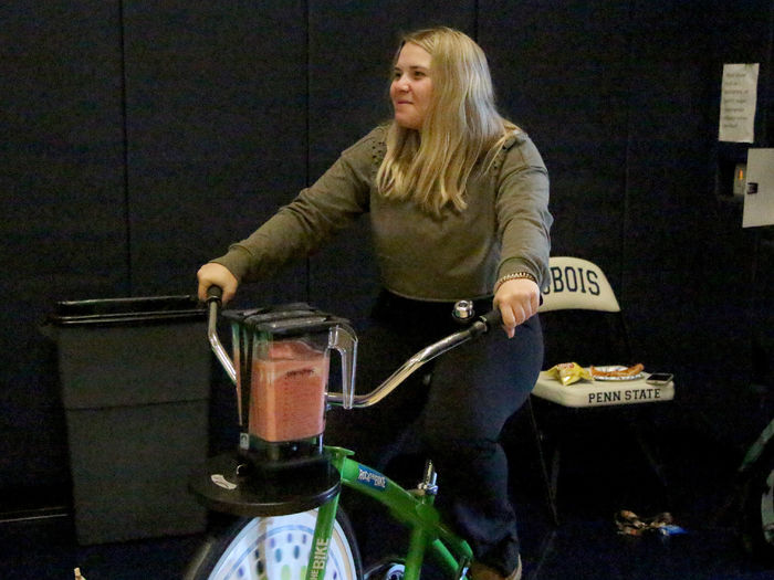 Penn State DuBois third-year student Makena Baney peddles the smoothy bike to make her smoothie during the Earth Day Celebration at Penn State DuBois.