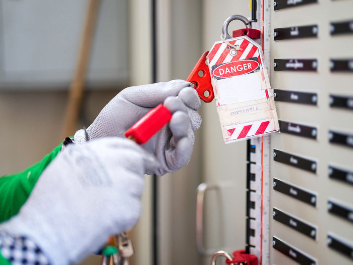 An employee, wearing proper safety protection, completes a lockout tagout procedure on a circuit breaker at the main distribution point.