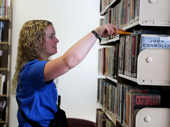 Incoming student Kamryn MacTavish dusts bookshelves at the DuBois Public Library during outreach day.