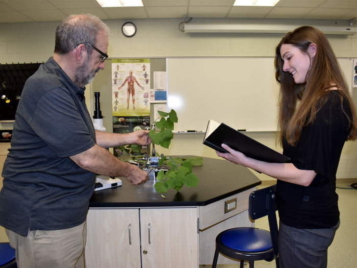Robert Loeb, left, studies a plant sample while Taylor Walborn, right, references the plant with historical data.
