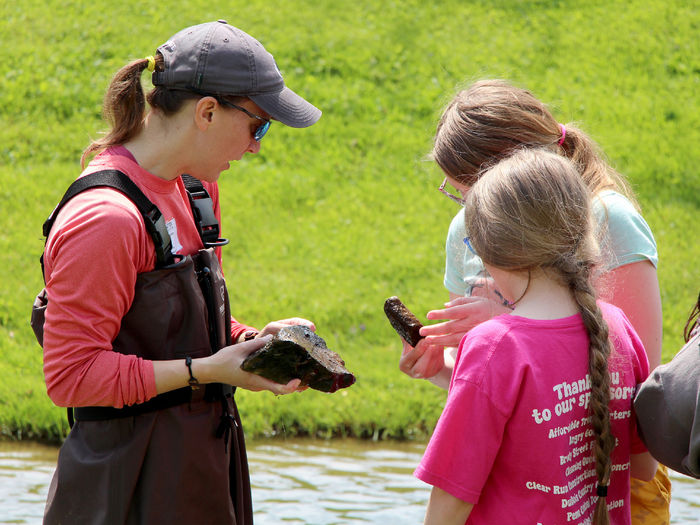 Emily Thomas, left, associate teaching professor of wildlife technology at Penn State DuBois, discusses organisms the students found on rocks within a wetlands area during the program session held at Juniata Elementary in DuBois in May.