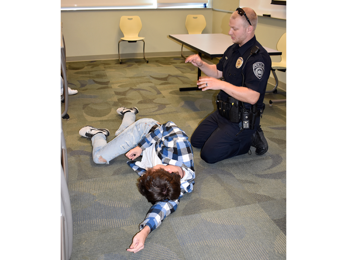 Officer Haag and a student volunteer demonstrate the recovery position to place someone unconscious in until help arrives.