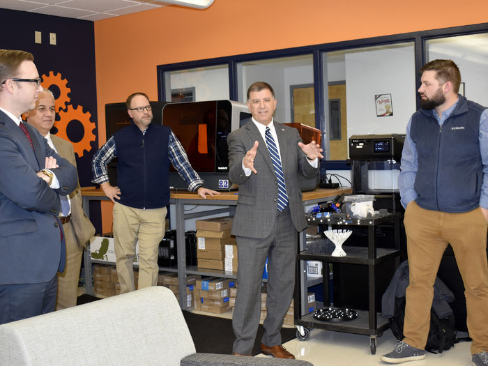 Brad Lashinsky, third from left, and John Williams, center, provide a demonstration of  3D scanning and printing equipment to the leadership at CNB Bank