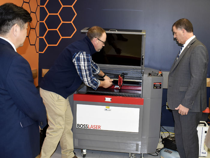 Brad Lashinsky, center, demonstrates the capabilities of one of the newest additions to the Idea Lab, a Boss laser engraver.