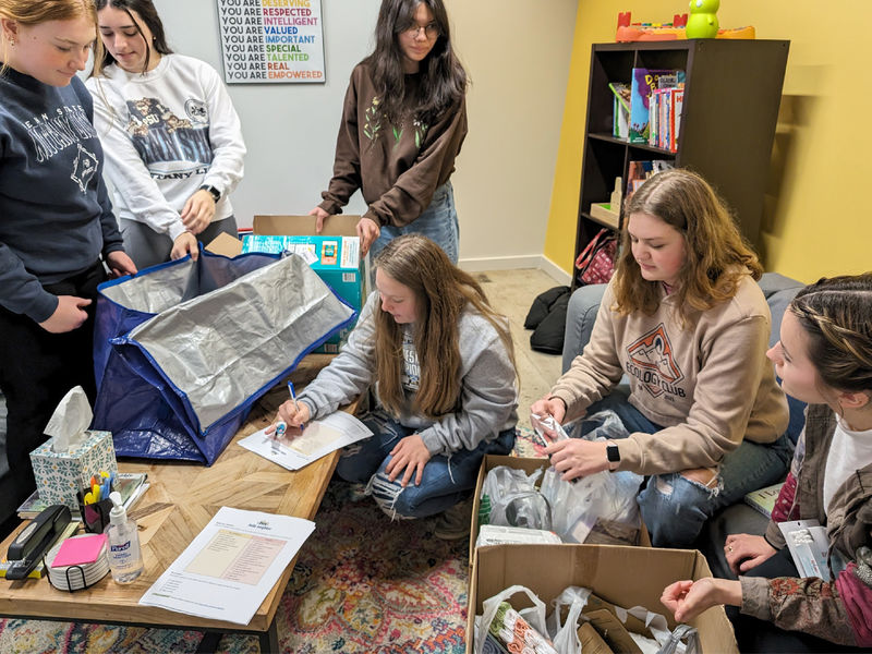 HDFS club members take inventory and organize items at Hello Neighbor during the process of making baby bags during their visit.