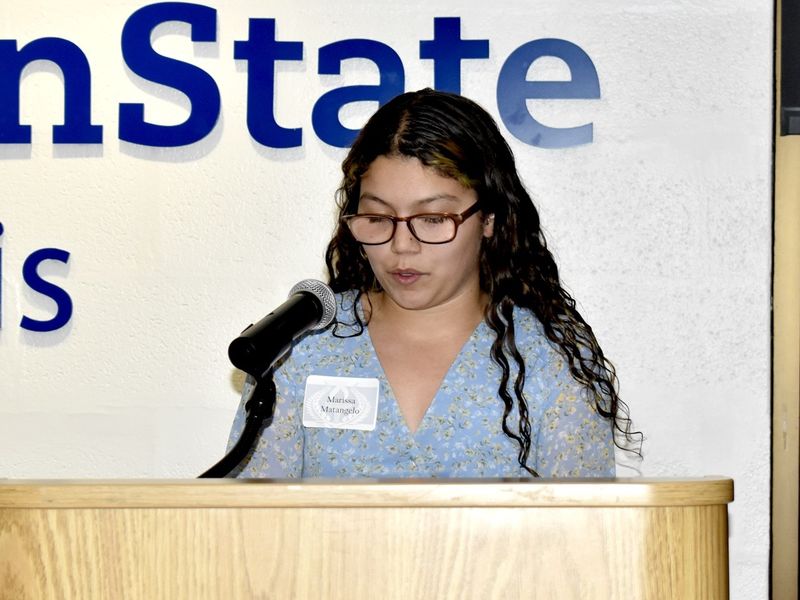 A person standing at a podium speaking into a microphone