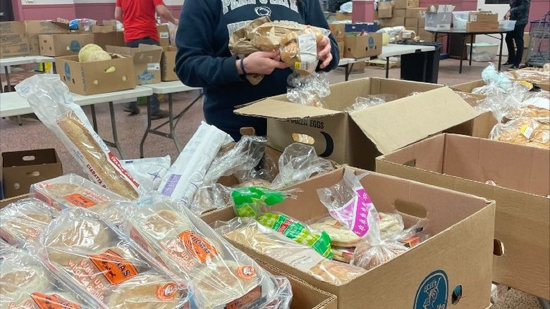 Student checking expiration dates on food at a food pantry