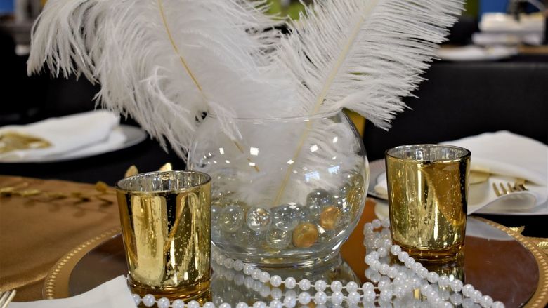Centerpiece at old Hollywood event with feathers, candles, and pearls