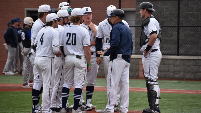 players huddle on the baseball hill with their coach during a game