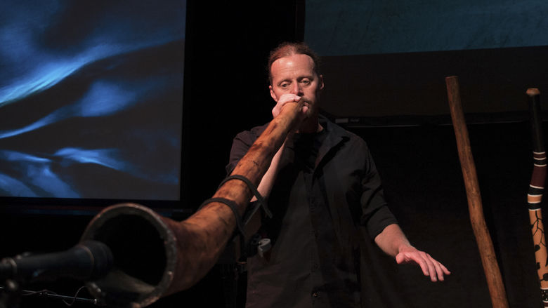 A person playing a didgeridoo into a microphone