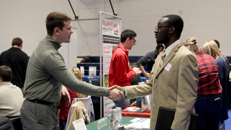 Kane Witter, right, shakes the hand of an employer representative during the career fair at Penn State DuBois in the PAW Center
