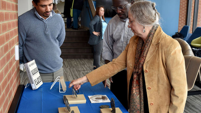 Jeanne Stevens-Sollman shares details of her metal workings with Amila Madiligama, assistant teaching professor in physics, left, and Daudi Waryoba, associate professor in engineering, during the “Let’s Represent Art Show”, held in February at Penn State DuBois