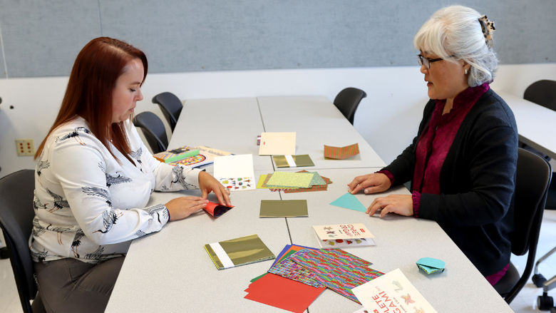 Hyeseon Kim, community outreach coordinator for the institute for Korean studies, right, guides Marly Doty, lecturer in human development and family studies, through an origami activity during the DEIB workshop held at Penn State DuBois in October.