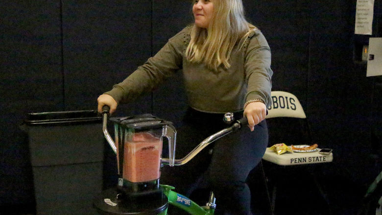 Penn State DuBois third-year student Makena Baney peddles the smoothy bike to make her smoothie during the Earth Day Celebration at Penn State DuBois.