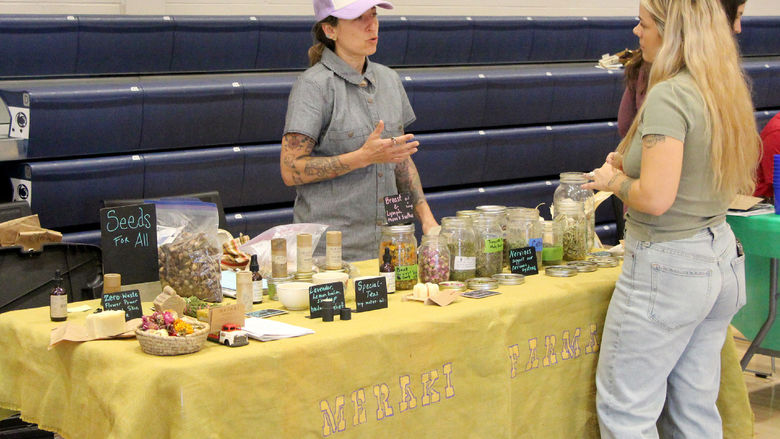 A representative from Meraki Farmacy discusses their products to an attendee during the Earth Day Celebration at Penn State DuBois.