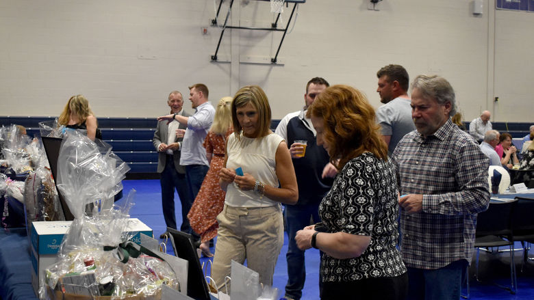 Attendees of the Lion Wine and Cheese fundraiser look over the items available in the basket raffle during the event at the PAW Center