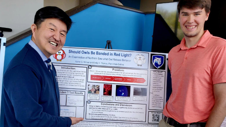 Two people stand in front of a research poster. 