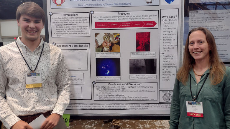 Two people stand in front of a trifold poster. 