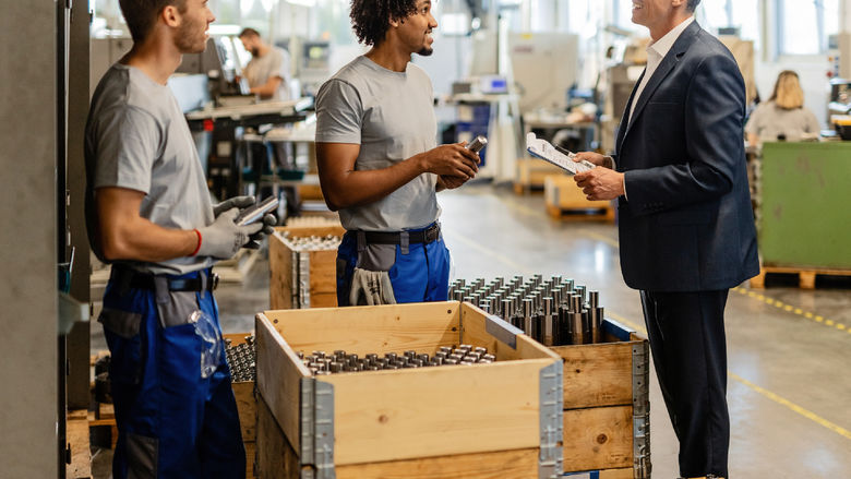 A supervisor discusses production with other employees on the manufacturing floor.