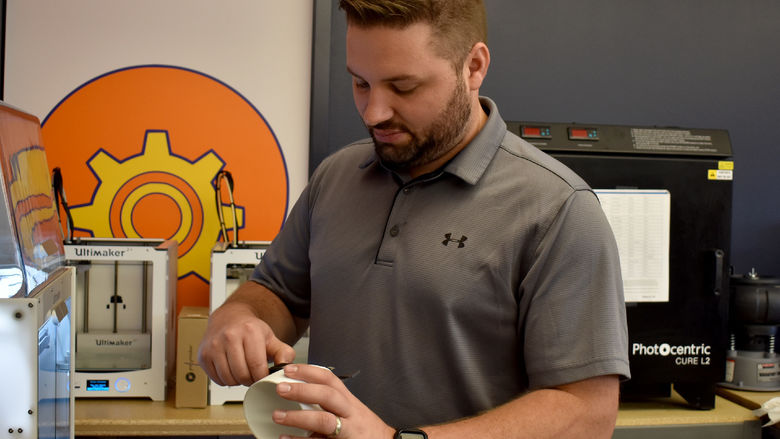 Johnny Williams, new engineering technologist for the NCPA LaunchBox, measures a prototype with calipers in the Idea Lab on the Penn State DuBois campus.