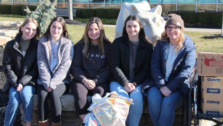 Five people in front of the lion shrine with boxes of food.