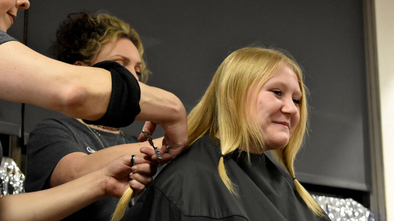 Abby Freemer has her hair cut after donations reach her goal during the THON hair auction
