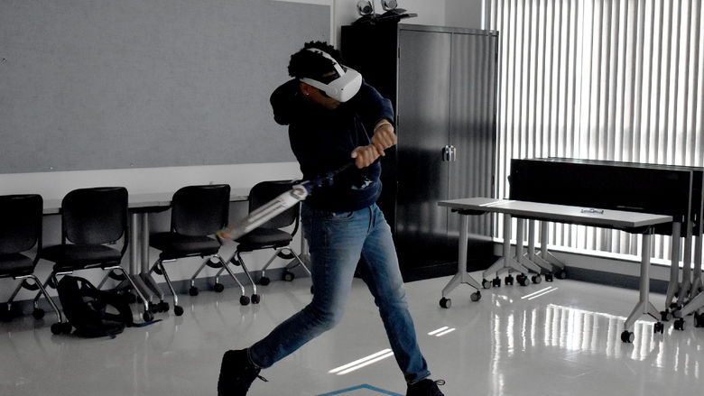 A baseball player from Penn State DuBois uses virtual reality equipment to practice hitting inside the DEF Building on campus