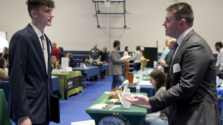 Penn State DuBois student Tristan Parker, left, talks with alumni Caleb Bennett, financial professional with Equitable Advisors, during the career fair at the PAW Center.