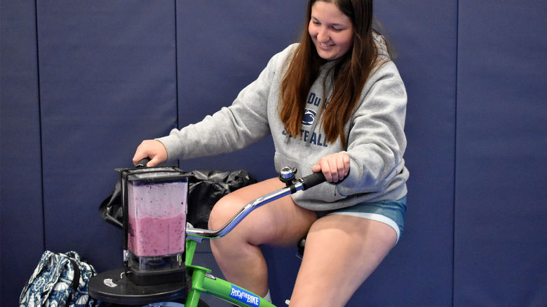 Penn State DuBois student Aleigha Geer pedals the smoothie bike during the 2023 Earth Day celebration at the PAW Center.