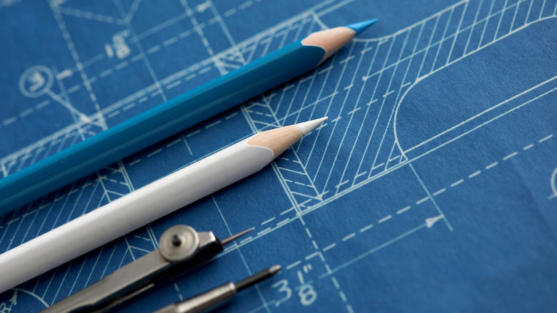 Markup tools lay on top of a blueprint on a table.