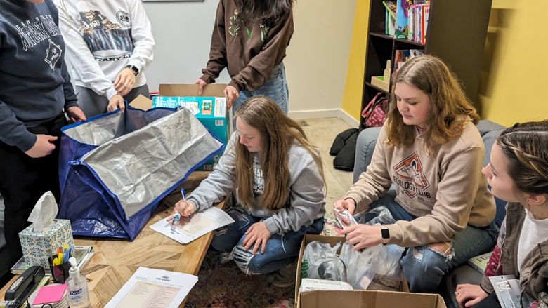 HDFS club members take inventory and organize items at Hello Neighbor during the process of making baby bags during their visit.