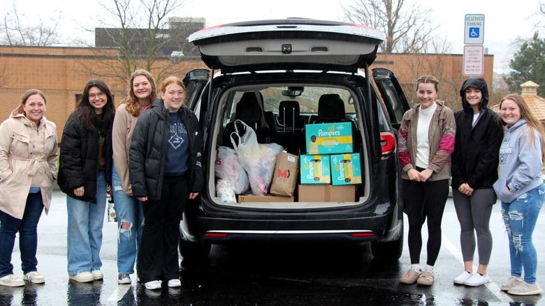 Members of the HDFS club at Penn State DuBois stand next to the vehicle loaded with their donation items prior to their trip to the Hello Neighbor location in Pittsburgh.