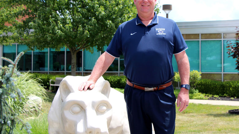 New head golf coach at Penn State DuBois John Schneider stands with the Lion Shrine on campus.
