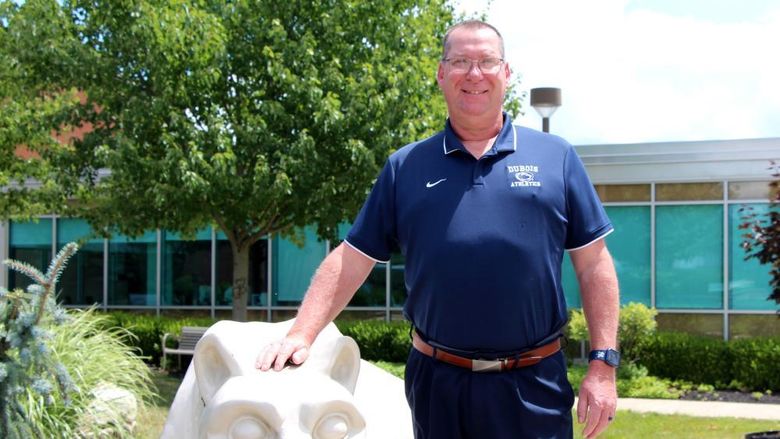New head golf coach at Penn State DuBois John Schneider stands with the Lion Shrine on campus.