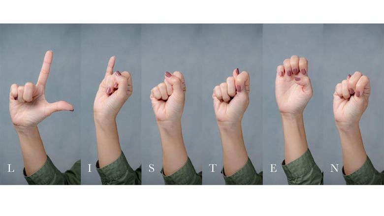 Hands gesturing using sign language to spell the word “listen”.