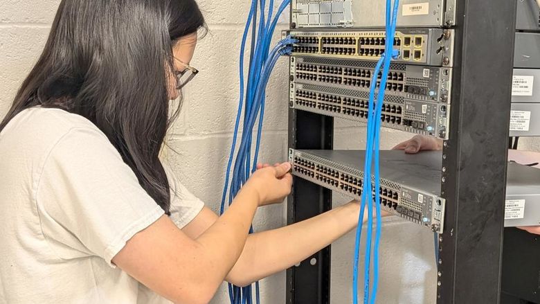 Penn State DuBois student Katy Fritz works on wiring and connecting one of the new Juniper switches that the campus received as part of the new partnership with Penn State IT.