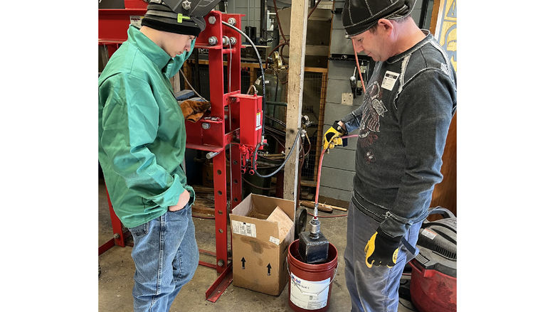 Dutch Manufacturing student Sam Rettger, left, and instructor Martin Casilio, test whether Rettger’s cube project is air-tight by submerging the project in water while connected to compressed air.