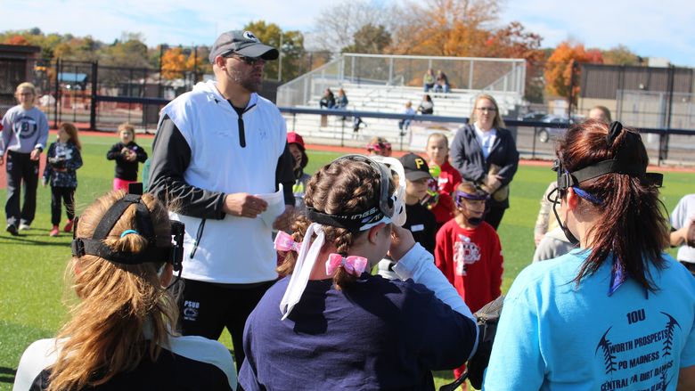 Coach Jason Kern leading softball camp participants at Heindl Field. 