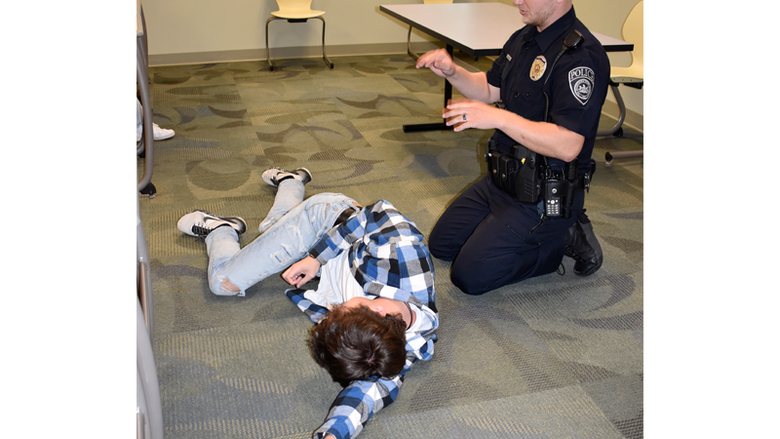 Officer Haag and a student volunteer demonstrate the recovery position to place someone unconscious in until help arrives.