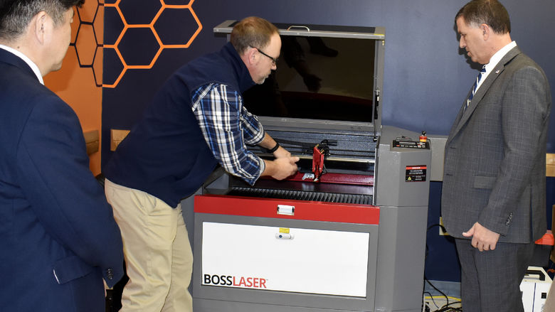 Brad Lashinsky, center, demonstrates the capabilities of one of the newest additions to the Idea Lab, a Boss laser engraver.