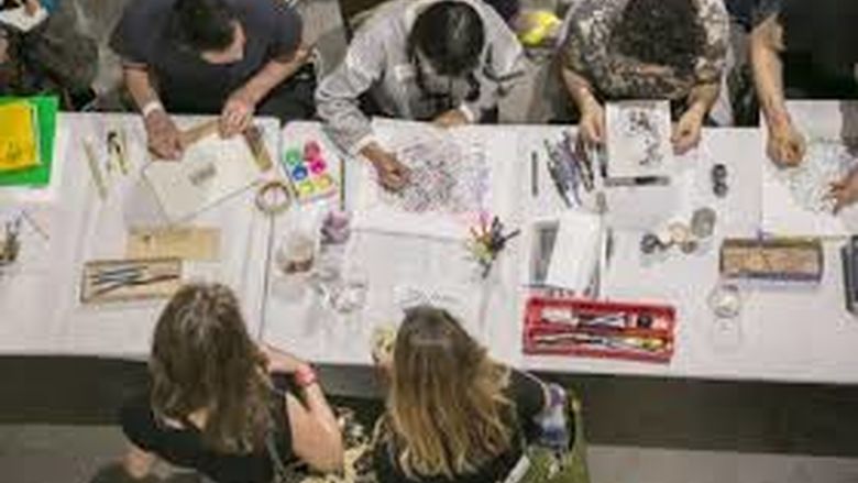 Five students drawing at a table