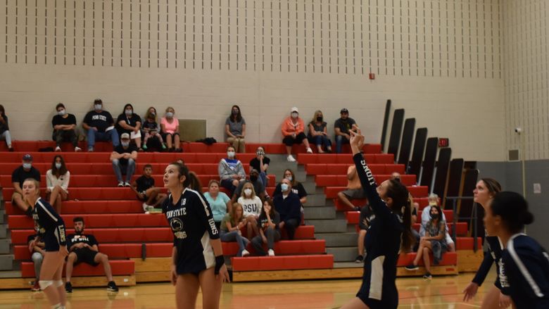 Volleyball players on court during a home match. 