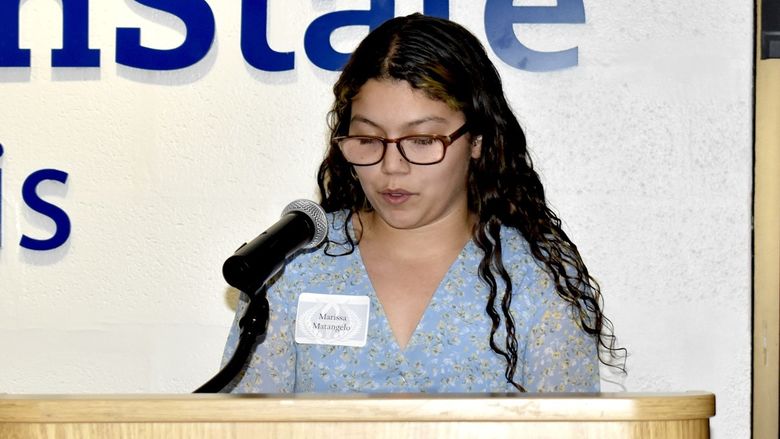 A person standing at a podium speaking into a microphone